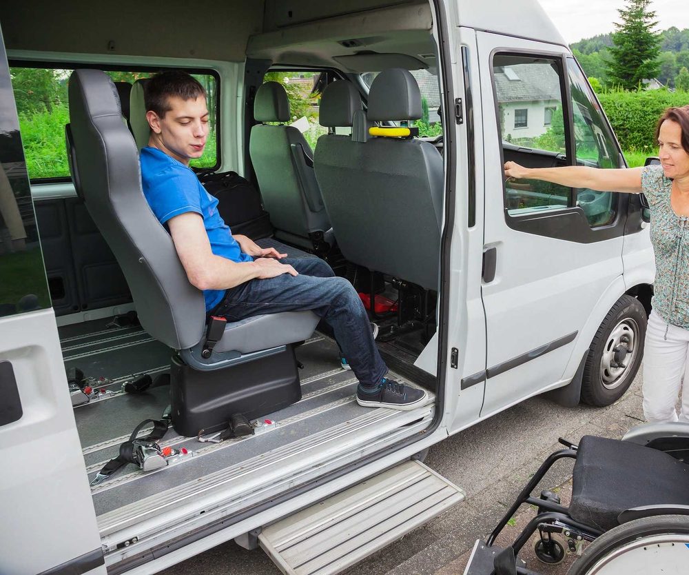 Caregiver helping a wheelchair user into an accessible vehicle for non-medical transportation